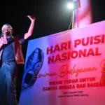 Seniman dan budayawan Arifin Sunusi mendeklamasikan puisinya dalam perayaan Hari Pusi Nasional di depan Kantor DPRD Sulteng, Sabtu (2/8/2025) malam. (©bmzIMAGES/basri Marzuki)