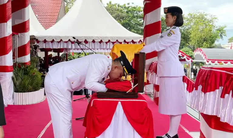 Wali Kota Palu Hadianto Rasyid mencium bendera merah putih sebelum diserahkan ke Paskibraka untuk dikibarkan di halaman Kantor Wali Kota Palu, Minggu (17/8/2025). (©Prokopim Steda Kota Palu)