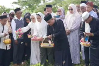 Wali Kota Hadianto rasyid dan Wawali Imelda Lilianan Muhidin menabur bunga saat ziarah korban bencana 28 September 2018 di Petobo. (© Prokopim Setda Kota Palu/Iwan)