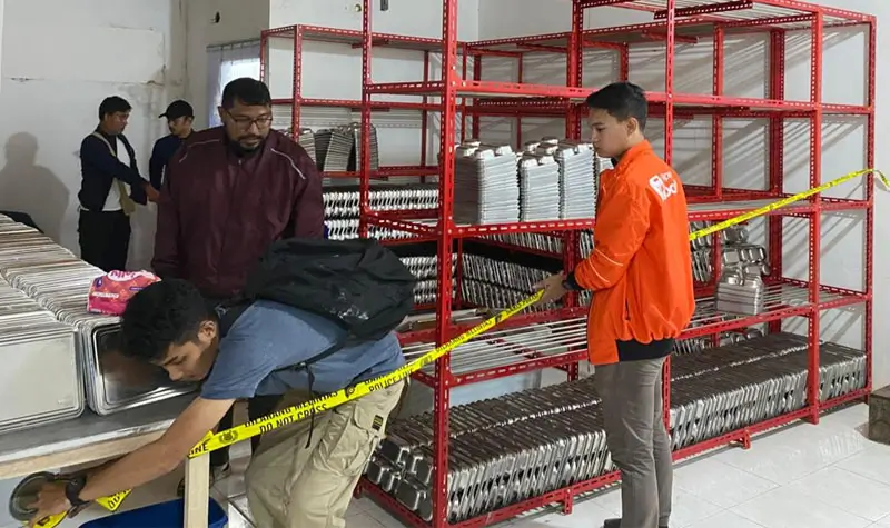 Petugas memasang garis polisi di SPPG MBG yang menyebabkan keracnunan massal siswa di Salakan, Bangkep, Kamis (18/9/2025). (©Humas Polres Bangkep)