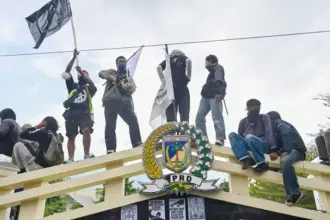 Sejumlah mahasiswa berada di atas pagar kantor DPRD Sutleng saat aksi unjuk rasa, Senin (1/9/2025). (©bmzIMAGES/basri marzuki)