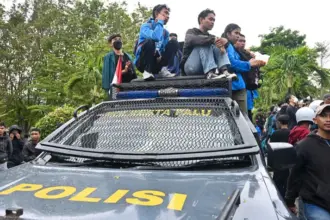 Sejumlah mahasiswa duduk di atas kendaraan penerangan polisi pada unjuk rasa damai di depan kantor DPRD Sulteng, Senin (1/9/2025). (©bmzIMAGES/basri marzuki)