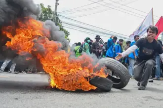 Seorang mahasiswa menggelindingkan ban bekas untuk dibakar pada aksi demonstrasi di depan Kantor DPRD Sulteng di Palu, Senin (1/9/2025). (©bmzIMAGES/basri marzuki)