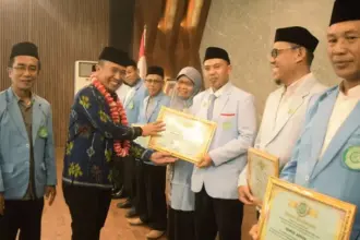 Plt. Asisten bidang Perekonomian dan Pembangunan Setda Kota Palu, Rahmad Mustafa menyerahkan piagam pada rangkaian pelantikan dan rakerda BKPRMI Kota Palu, Sabtu (20/9/2025). (©Prokopim Setda Kota PAlu/Imron)