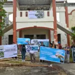 Sejumlah seniman membentangkan spanduk di depan gedung pertunjukan yang rusak di kawaan Taman Budaya Palu, Sabtu (27/9/2025). (© bmzIMAGES/basri marzuki)