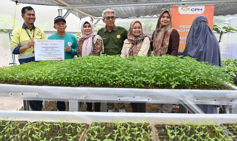 Supervisor CSR PT CPM, Zulkifli Salingkat (kiri) menyerahkan bibit tanaman cabai kepada Ketua Kelompok Tani Mitra Poboya di Kelurahan Poboya, Palu, Sulawesi Tengah, Kamis (2/10/2025). (© bmzIMAGES/basti marzuki)