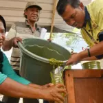 Supervisor CSR PT CPM, Zulkifli Salingkat (kanan) membantu petani menuangkan adonan bahan organik ke dalam wadah pada pelatihan pembuatan pupuk organik cair di Kelurahan Poboya, Palu, Sulawesi Tengah, Kamis (2/10/2025). (© bmzIMAGES/basti marzuki)