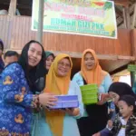 Wakil Wali Kota Palu, Imelda Liliana Muhidin menyerahkan makanan tambahan kepada anak pada peluncuran Dapur Sehat Mompakabelo Rumah Gizi PKK Kelurahan Lolu Utara, Kecamatan Palu Timur, Rabu (1/10/2025). (© Prokopim Setda Kota Palu/Imron)