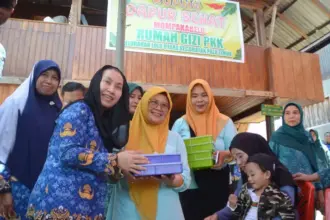 Wakil Wali Kota Palu, Imelda Liliana Muhidin menyerahkan makanan tambahan kepada anak pada peluncuran Dapur Sehat Mompakabelo Rumah Gizi PKK Kelurahan Lolu Utara, Kecamatan Palu Timur, Rabu (1/10/2025). (© Prokopim Setda Kota Palu/Imron)