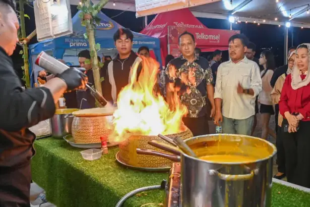 Wawali Imelda (kiri) menyaksikan pramu saji menyiapkan makanan pesanan pembeli pada Festival Kuliner Palu Raasa Bangkok di PGM Palu, Rabu (1/10/2025) malam. (© Prokopim Setda Kota palu/Jufri)