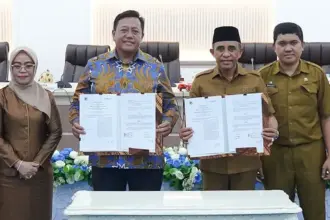 Gubernur Anwar Hafid bersama Dirut PT Telkomsat Lukman Hakim Abdul Ra'uf menunjukkan naskah Mou usai di teken di Palu, Selasa (21/10/2025). (©PPID DIskominfosantik Sulteng)