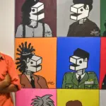 Perupa Wiyoso Yoganingrat alias Iwin berdiri di dekat karya lukisnya pada pameran tunggal di Ondewe Cafe, Palu, Sulawesi Tengah, Senin (17/11/2025) malam. ©bmzIMAGES/Basri Marzuki)