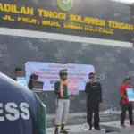 Sejumlah jurnalis membawa pamplet saat menggelar aksi mimbar beas di depan Kantor Pengadilan Tinggi SUlteng, Minggu (16/11/2025). (©KKJ Sulteng)