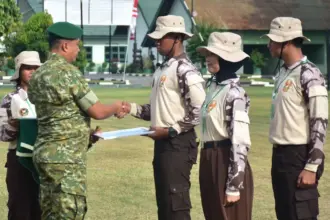 Danem 132/Tadulako, Brigjen TNI Deni Gunawan menyerahkan sertifikat kepad asalah seorang Kadet pada penutupan Persami KKRi di Yonif 711/Raksatama Palu, Minggu (2/11/2025). (©Pendam23)