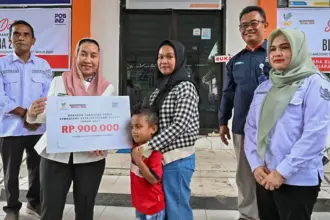 Waali Imleda disaksikan GM PT Pos Indonesia Palu Supriantoro menyerahkan secara simbolis BLTS Kesra 2025 di halaman Kantor Pos Palu, Rabu (26/11/2025). (©bmzIMAGES/Basri Marzuki)