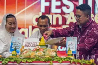 Kepala OJK Sulteng Bonny Hadi Putra (kanan) bersama Wawali Palu Imelda Liliana Muhidin (kiri) memotong tumpeng menandai peringatan HUT ke-14 OJK sekaligus puncak Festival UMKM dan Akses Permodalan di LapanganVatulemo, Palu, Sabtu (22/11/2025). (©Prokopim Setda Kota Palu/Jufri)