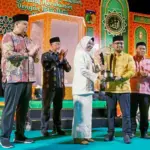 Asisten Administrasi Umum Setda Kota Palu, Eka Komalasari menyerahkan piala kepada kontingan Palu Selatan yang meraih juara umu pada MTQ ke-28 di Tipo, Ulujadi, Rabu (4/11/2025). (©Prokopim Setda Kota Palu/Yuspi)