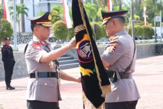 Pejabat Kapolda lama Irjen Pol Agus Nugroho (kanan) menyerahkan pataka kepada pejabat Kapolda baru, Irjen Pol Endi Sutendi di Mapodla Sulteng, Senin (3/11/2025). (©Humas Polda Sulteng)