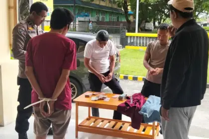 Petugas menata barang bukti uang hasil pencurian di depan pelaku di Mapolsek Tawaeli, Palu, Senin (17/11/2025). (©HUmas Polresta Palu)
