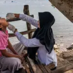 Rani Amsa, bidan dari Puskesmas Peukan Bada, memberikan imunisasi polio di dekat pantai di Aceh Besar, Aceh, saat Pekan Imunisasi Nasional pada bulan Desember 2022. (©WHO/Fauzan Ijazah)