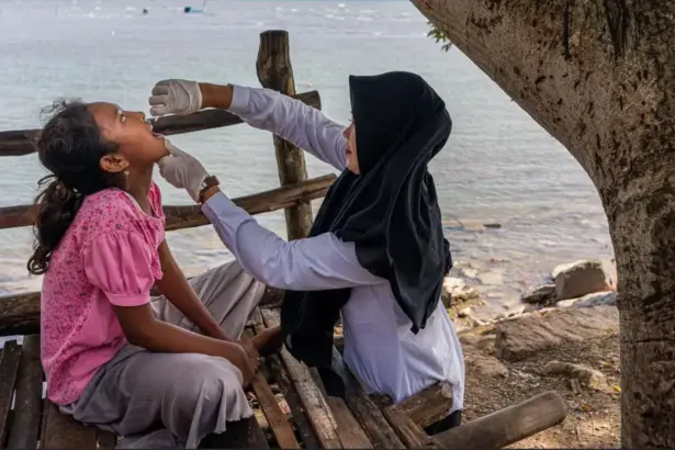 Rani Amsa, bidan dari Puskesmas Peukan Bada, memberikan imunisasi polio di dekat pantai di Aceh Besar, Aceh, saat Pekan Imunisasi Nasional pada bulan Desember 2022. (©WHO/Fauzan Ijazah)