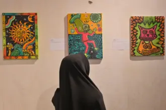 Pengunjung memperhatikan lukisan yang dipajang pad apameran lukisan Ruang Rupa Rasa di Rumah Tiara Coffee, Palu, Minggu (9/11/2025) malam. (©bmzIMAGES/Basri Marzuki)