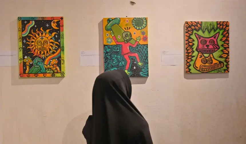 Pengunjung memperhatikan lukisan yang dipajang pad apameran lukisan Ruang Rupa Rasa di Rumah Tiara Coffee, Palu, Minggu (9/11/2025) malam. (©bmzIMAGES/Basri Marzuki)