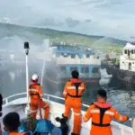 Petugas menyemprot KM Harapanku Mekar yang terbakar di pelabuhan Luwuk, Jumat (5/12/2025). (©Basarnas Palu)