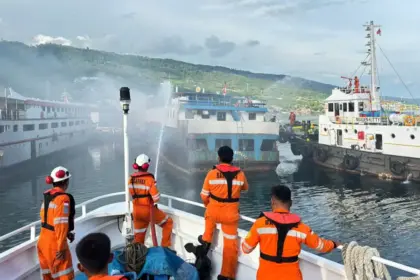 Petugas menyemprot KM Harapanku Mekar yang terbakar di pelabuhan Luwuk, Jumat (5/12/2025). (©Basarnas Palu)