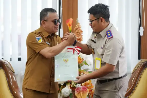 Kepala Kantor BPN Kota Palu, Susetyo Nugroho menyerahkan sertifikat aset milik Pemkot Palu kepada Wali Kota Palu, Hadianto Rasyid di ruang kerja Wali Kota Palu, Selasa (30/12/2025). (©Prokopim Setda Kota Palu/Jufri)