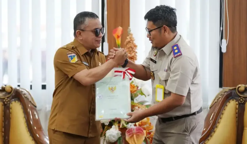 Kepala Kantor BPN Kota Palu, Susetyo Nugroho menyerahkan sertifikat aset milik Pemkot Palu kepada Wali Kota Palu, Hadianto Rasyid di ruang kerja Wali Kota Palu, Selasa (30/12/2025). (©Prokopim Setda Kota Palu/Jufri)