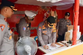 Kapolresta Palu Kombes Pol Deny Abrahams mengisi buku tamu saat melakukan inspeksi ke salah satu Pos Pengamanan Natura di Palu, Rabu (24/12/2025). (©Humas Polresta Palu)