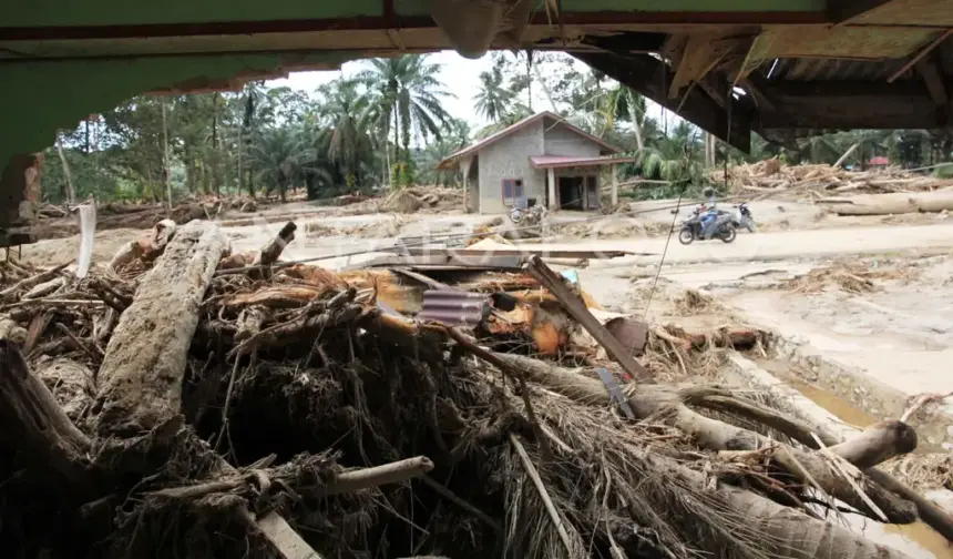 Warga melintas di area rumah yang terdampak banjir bandang di Desa Aek Garoga, Kecamatan Batang Toru, Tapanuli Selatan, Sumatera Utara, Senin (1/12/2025). Berdasarkan data dari BPBD Tapanuli Selatan Senin (1/12) diwilayahnya sebanyak 50 orang meninggal dunia dan 46 orang belum ditemukan akibat bencana banjir bandang dan longsor pada Selasa (25/11).ANTARA FOTO/Yudi Manar/YU
