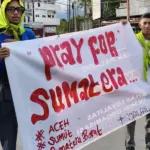 Anggota PALADO membentangkan spanduk pada aksi penggalangan dana untuk bencana SUmatera di Sigi, Sabtu (20/12/2025). (©Palado)