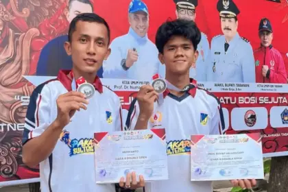 Pratu Heriyanto (kiri) menunjukkan medalinya usai memenangkan pertandingan pada Open Petanque Competition 2025 di Tabanan, Bali, Selasa (30/12/2025). (©Pendam23)