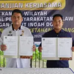 Kakanwil Ditjenpas Sulteng Bagus Kurniawan (kiri) dan Asisten Manajer Bukit Indah Doda Hotel & Resort Rizal menuynjukkan naskah PKS usai diteken di kebun asimiliasi Lapas Palu, Rabu (14/1/2026). (©Humas Ditjenpas Sulteng)