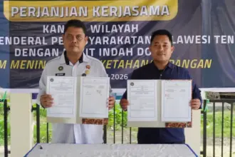 Kakanwil Ditjenpas Sulteng Bagus Kurniawan (kiri) dan Asisten Manajer Bukit Indah Doda Hotel & Resort Rizal menuynjukkan naskah PKS usai diteken di kebun asimiliasi Lapas Palu, Rabu (14/1/2026). (©Humas Ditjenpas Sulteng)