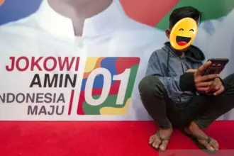 Ilustrasi - Seorang remaja memainkan gawainya di depan baliho pasangan calon Presiden dan Wakil Presiden. ANTARA FOTO/Basri Marzuki/foc/am.