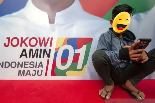 Ilustrasi - Seorang remaja memainkan gawainya di depan baliho pasangan calon Presiden dan Wakil Presiden. ANTARA FOTO/Basri Marzuki/foc/am.