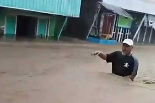 Warga menerobos banjir di Desa Wani, DOnggala, Minggu (11/1/2026). (©Tangkapan layar warga)