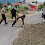 Sejumlah anggota polisi menambal jalan yang berlubang di Desa Kotapulu, Sigi, Senin (5/1/2026). (©Humas Polres Sigi)