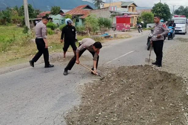Sejumlah anggota polisi menambal jalan yang berlubang di Desa Kotapulu, Sigi, Senin (5/1/2026). (©Humas Polres Sigi)