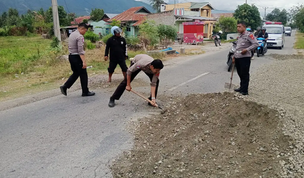 Sejumlah anggota polisi menambal jalan yang berlubang di Desa Kotapulu, Sigi, Senin (5/1/2026). (©Humas Polres Sigi)