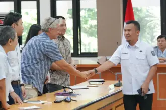 Plt. Asisten Bidang Perekonomian dan Pembangunan Setda Kota Palu, Rahmad Mustafa (kanan) menyalami delegasi Myanmar pada sharing pemulihan pascabencana di palu, Rabu (25/2/2026). (©Prokopim Setda Kota Palu/Jufri)
