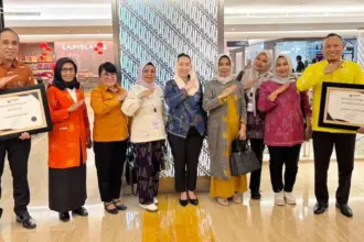 Waali Palu Imelda Liliana Muhidin (tengah) bersama Kepala DPmPTSP dan Kepala Puskesmas Talise menunjukkan sertifikat penghargaan yang baru diteriam dari Kemen PAN-RB di Jakarta, Rabu (11/2/2026). (©Diskominfosantik Palu)