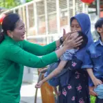 Ketua Persit KCK Daerah XXIII/Palaka Wira, Dewi Binsar menyapa seorang anak pada bakti sosial HUT ke-80 Persit KCK di palu, Minggu (15/2/2026). (©Pendam23)