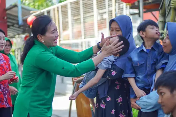 Ketua Persit KCK Daerah XXIII/Palaka Wira, Dewi Binsar menyapa seorang anak pada bakti sosial HUT ke-80 Persit KCK di palu, Minggu (15/2/2026). (©Pendam23)