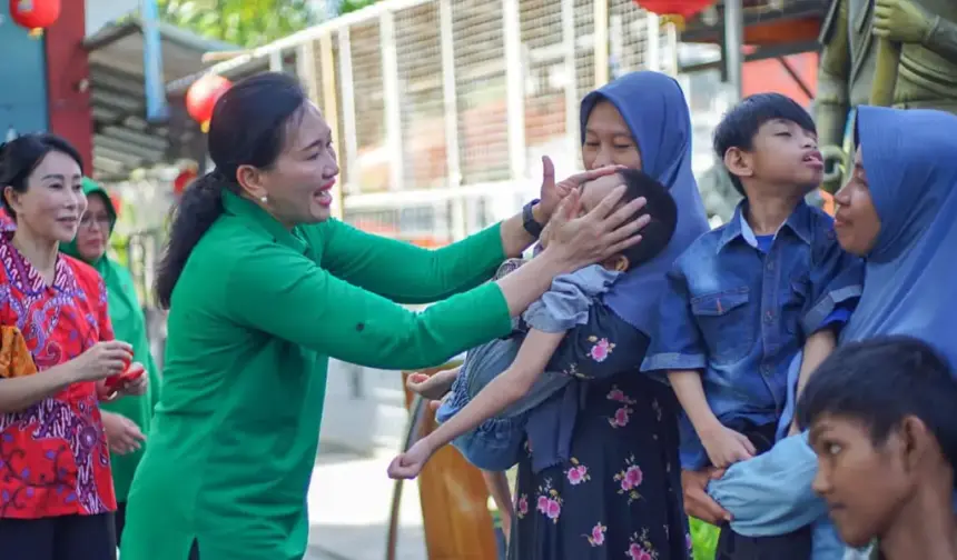 Ketua Persit KCK Daerah XXIII/Palaka Wira, Dewi Binsar menyapa seorang anak pada bakti sosial HUT ke-80 Persit KCK di palu, Minggu (15/2/2026). (©Pendam23)