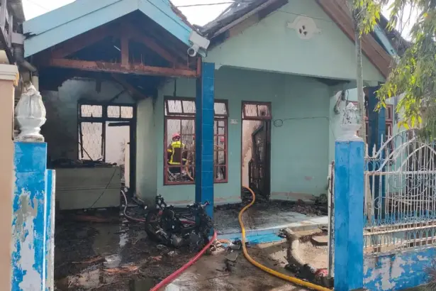 Petugas memadamkan api yang membakar rumah di BTN Bumi Anggur Palu, Minggu (15/2/2026). (©Humas Polresta Palu)
