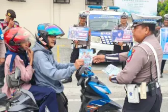 Kasatlantas Polresta Palu, AKP Atmaji Sugeng Wibowo membagikan brosur kepada pengendara pada Operasi Keselamatan Tinombala 2026 di Palu, Kamis (12/2/2026). (©Humas Polresta Palu)